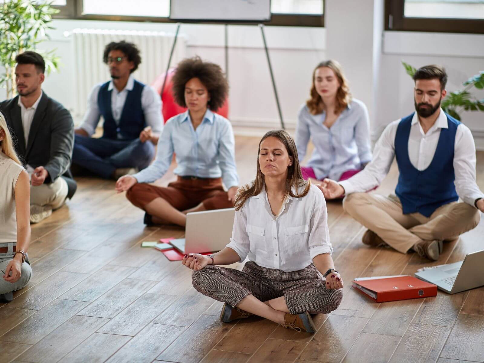 Coworkers meditating together, sitting on the floor